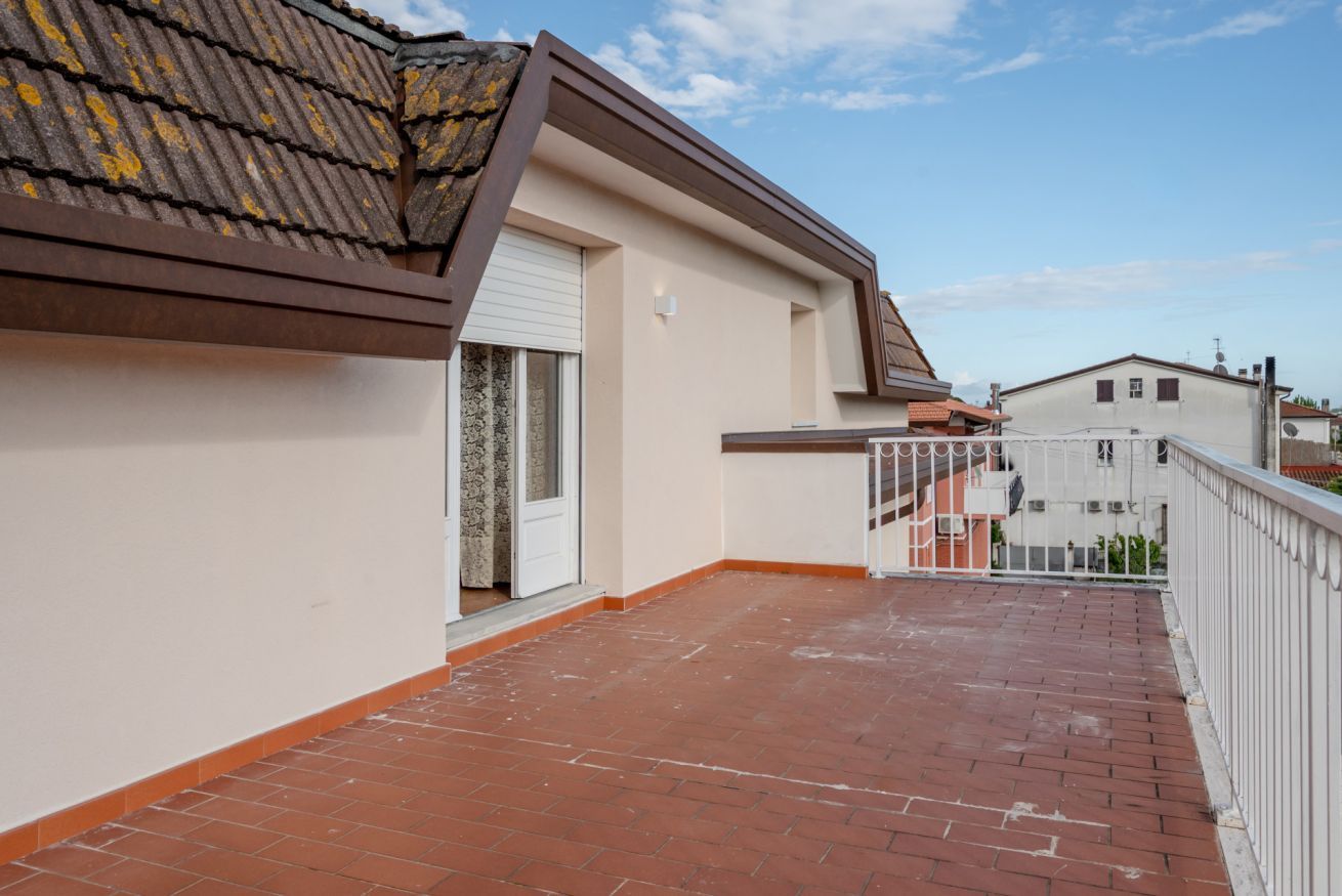 Ein Wohngebäude mit einem roten Ziegeldachbalkon, einer weißen Tür und einem weißen Geländer.