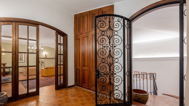 Una stanza con un armadio in legno, un divisorio metallico decorativo e un pavimento piastrellato.