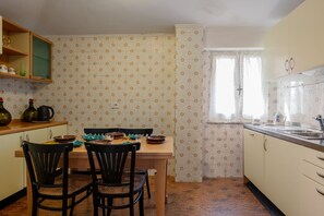 Una cocina con una mesa de comedor, sillas y una ventana con cortinas.