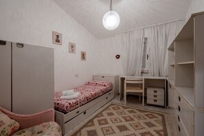 Un dormitorio con cama, escritorio, armario e iluminación colgante.