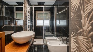 Een moderne badkamer met een grote wastafel, een losstaande wastafel, een douche met glazen wanden en een toilet.