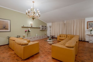 Una sala de estar con un sofá, una lámpara de araña, una mesa de centro y una chimenea.