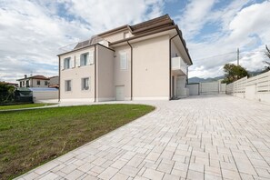 Ett modernt hus i två våningar med en asfalterad uppfart och en liten gräsmatta.