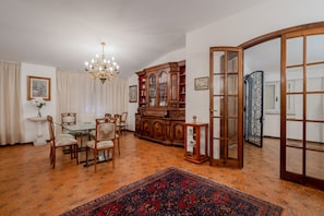 Comedor con candelabro, muebles de madera y alfombra estampada.