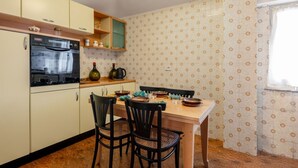 Een keuken met een eettafel, stoelen en een fornuis.