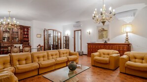 Un soggiorno con divani in pelle, un tavolino in vetro, un lampadario e mobili in legno.