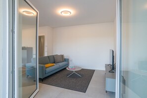 Una sala de estar moderna con un sofá, una mesa de centro y un televisor sobre un mueble.