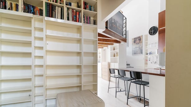 Un intérieur moderne comprenant une bibliothèque, un coin repas et une cuisine.