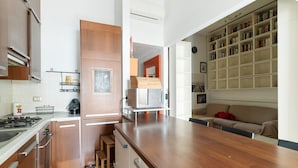 Une cuisine moderne avec des meubles en bois, un four à micro-ondes encastré et un coin repas doté d’une table en bois.