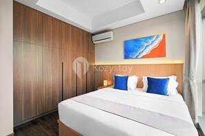 A modern hotel room with a large bed, wooden wardrobe, and a painting on the wall. - Shika by Kozystay - TB Simatupang (Jakarta)