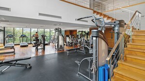 Ένα σύγχρονο γυμναστήριο με διαδρόμους, όργανα για ασκήσεις με βάρη και μια σκάλα.