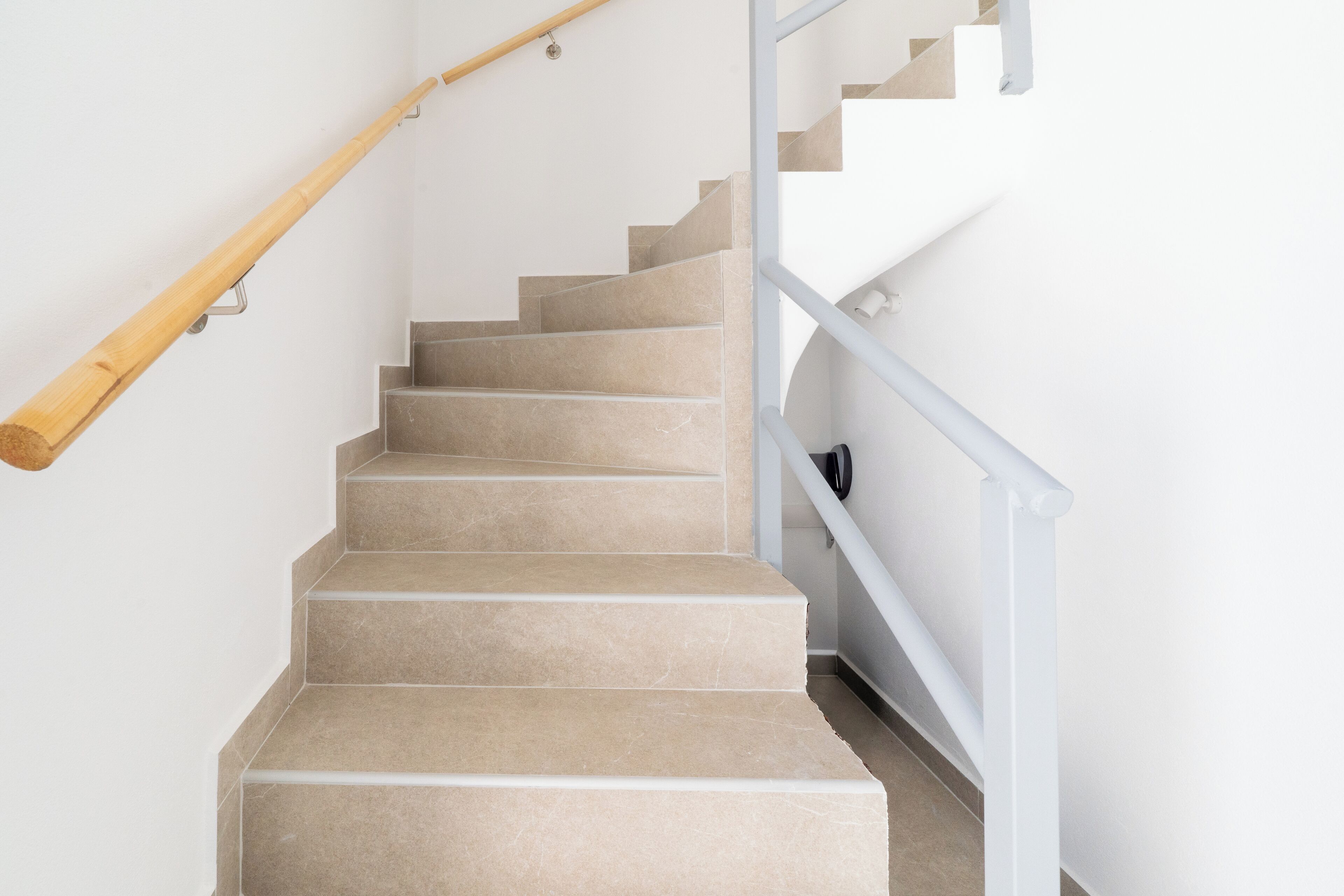 A staircase with beige steps and a wooden handrail.