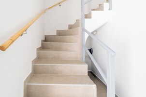 A staircase with beige steps and a wooden handrail.