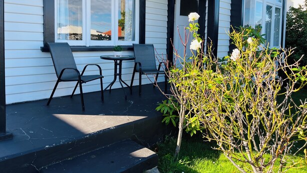 Ein Haus mit Veranda, zwei Stühlen, einem kleinen Tisch und einem Blumentopf.