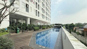 A modern building with a swimming pool, surrounded by greenery and a wooden deck. - Serpong Garden NATURE INN (Cisauk)