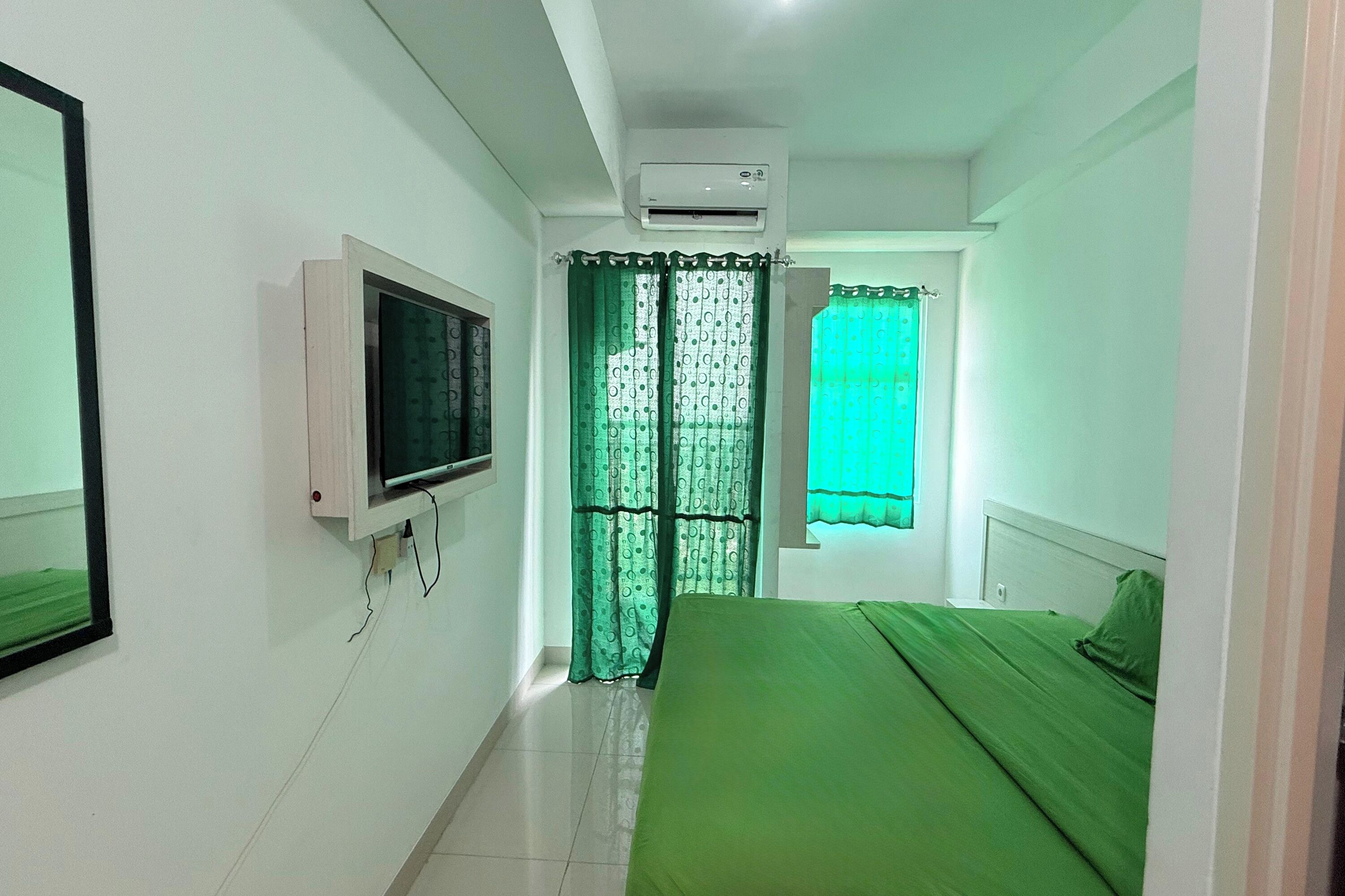A bedroom with a bed, a TV mounted on the wall, and an air conditioning unit on the ceiling.