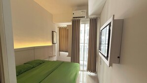 A bedroom with a bed, curtains, an air conditioning unit, and a window. - Serpong Garden NATURE INN (Cisauk)