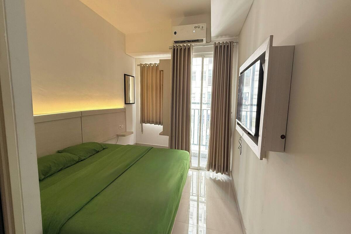 Ein Hotelzimmer mit Bett, einem Vorhangfenster, einer Klimaanlage und einem wandmontierten Fernseher.