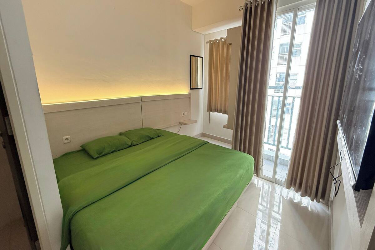 Ein Hotelzimmer mit Bett, Fenster mit Vorhängen und Blick nach draußen.