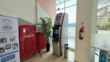 Een kapperszaak met een rode kast, een BRI geldautomaat en een brandblusser.