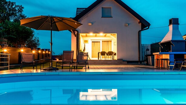Ein Haus mit Schwimmbad, Sitzgelegenheiten im Freien und Grillplatz.
