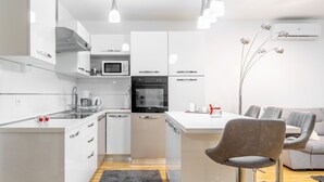 Eine moderne Küche mit weißen Schränken, einem Einbauofen und einer Kaffeemaschine.