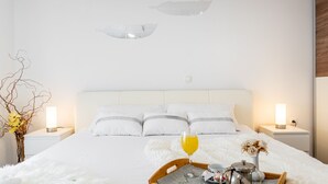 Ein Hotelzimmer mit einem großen Bett, zwei Nachttischen, einer Vase mit Blumen, einer Ablage mit einem Glas Saft und einem Wasserkocher.