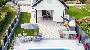 Ein Wohnhaus mit Swimmingpool, Sitzgelegenheit im Freien und einem umzäunten Garten.