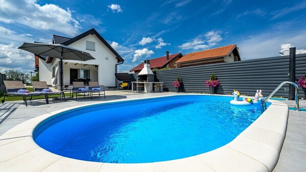 A swimming pool with lounge chairs and a barbecue area.