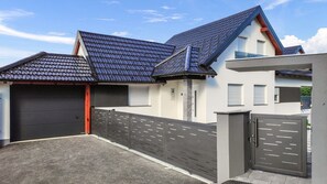 A modern two-story house with a garage, a covered driveway, and a gated entrance.