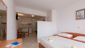 Habitación de hotel con cama, escritorio con un libro, una silla y vistas a la cocina y al comedor.