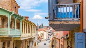 A narrow street with buildings on either side, featuring balconies and traditional architecture.