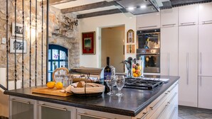 A modern kitchen with a granite countertop, stainless steel appliances, and a stone accent wall.