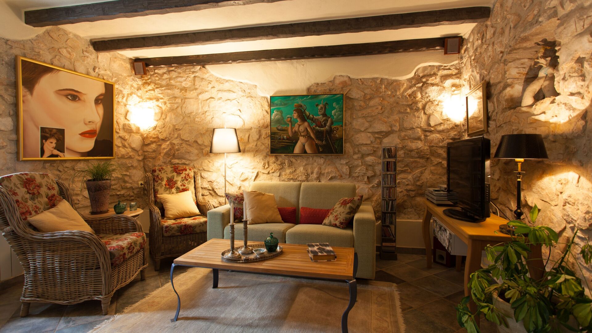 Un salon chaleureux avec des murs en pierre, un canapé, une table basse et un téléviseur.