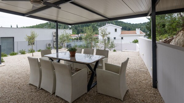 Un patio al aire libre cubierto con una mesa y sillas, rodeado de grava y plantas.