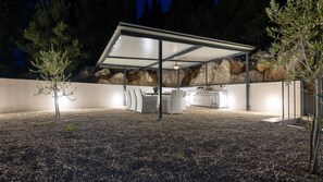 An outdoor patio area with a covered seating area, a barbecue grill, and a stone wall backdrop. - Villa Juma by Villas Guide (Blace)