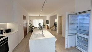 A modern kitchen with white cabinetry, a built-in island with a sink, and a large refrigerator with multiple compartments.