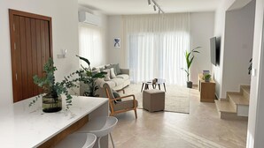 A modern living room with a sofa, a coffee table, and a TV mounted on the wall.