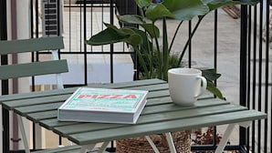 A balcony with a table, a book, and a potted plant.