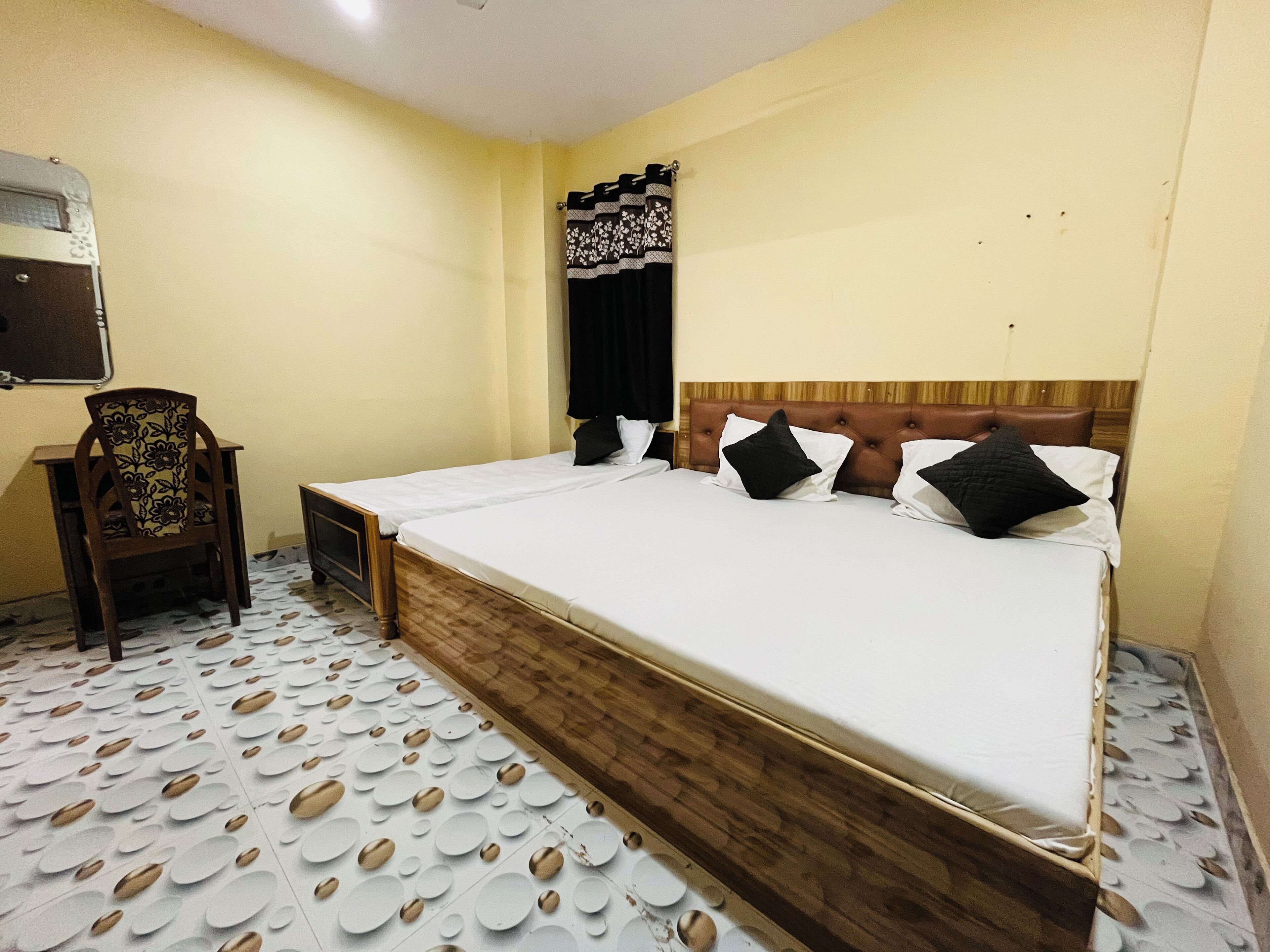 Ein Hotelzimmer mit einem großen Bett, einem Holzkopfende, einem Sessel und einem gemusterten Boden.