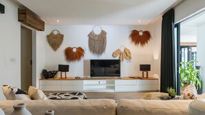 A modern living room with a sofa, TV, and decorative wall hangings.