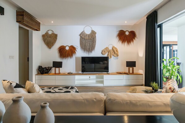 A modern living room with a sofa, TV, and decorative wall hangings.