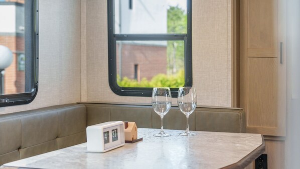 A small table with two wine glasses and a clock in a cozy, windowed space. - Sokcho Supuro Caravan (Sokcho)