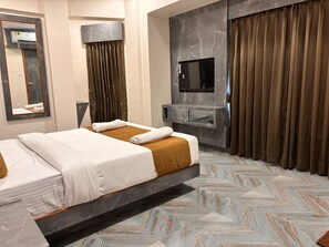 A modern hotel room with a bed, a flat-screen TV, a vanity, and a large window with curtains. - HOTEL ARTS PALACE (Mumbai)