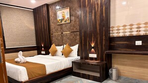Une chambre d’hôtel moderne dotée d’un grand lit, d’une table de chevet, d’un petit coin salon et d’un luminaire fixé au mur.