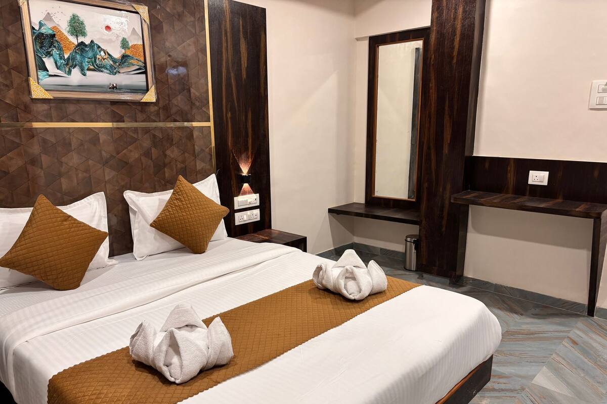 Een hotelkamer met een groot bed, een nachtkastje, een spiegel en een kunstwerk aan de muur.
