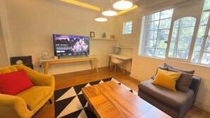 A living room with a television, a sofa, a coffee table, and a desk.