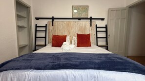 A bedroom with a bed, a headboard, a shelf, and a door.