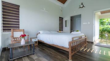 A bedroom with a wooden bed, a bedside table, a chair, and a window with blinds.