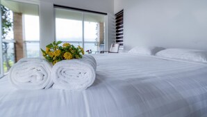 A neatly made bed with white linens and a bouquet of yellow flowers. - Floresta resorts (Idukki)